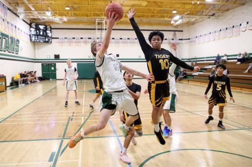 Bryant Whalen (14) drives toward the basket for the Neelin Spartans while Sid Morales of the Neepawa Tigers tries to block his shot during Brandon Sun Spartan Invitational Tier 2 action at Neelin on Friday. (Tim Smith/The Brandon Sun)