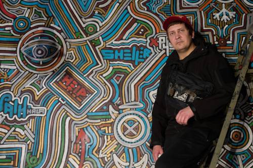 Ukrainian street artist Maxim Kilderov stands by his painting containing symbols and messages of resistance in his private museum that displays a collection of battlefield artifacts documenting Russia&rsquo;s invasion of Ukraine in Kyiv, Ukraine, on Tuesday. Russia&rsquo;s ongoing invasion Ukraine is just one example of the challenges the world faces as it moves into 2026, writes Kyle Volpi Hiebert. (The Associated Press)