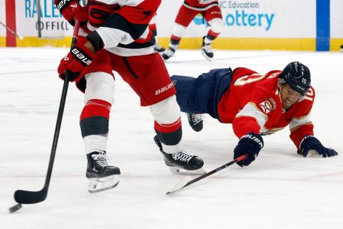Florida Panthers' A.J. Greer (10) dives at the puck controlled by Carolina Hurricanes' Shayne Gostisbehere (4) during the third period of an NHL hockey game, in Raleigh, N.C., Tuesday, Dec. 23, 2025. (AP Photo/Karl DeBlaker)