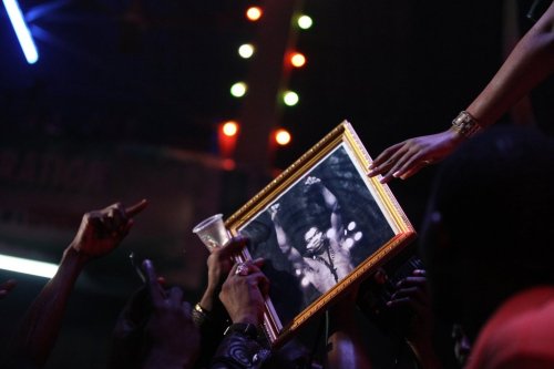 FILE - Singer Tiwa Savage hands back a portrait of Fela Anikulapo-Kuti to a fan at the New Afrika Shrine in Lagos, Nigeria, on Sunday, Oct. 21, 2012. (AP Photo/Jon Gambrell, File)