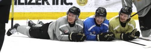 Brandon Wheat Kings forwards Caleb Hadland (left to right), Jordan Gavin and Joby Baumuller smile as they watch the shootout following the main practice at Assiniboine Credit Union Centre on Tuesday. The players stand at the blue-line awaiting their turn until they score, and then move to the side to stand, sit or lie to watch their teammates. (Perry Bergson/The Brandon Sun)