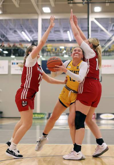 Ella Averill (13) of the Brandon Bobcats drives between Mattea Teece (11) and Sarah Boitson (14) of the University of Winnipeg Wesmen during Canada West women&rsquo;s basketball action at the Healthy Living Centre on Friday evening. (Tim Smith/The Brandon Sun)