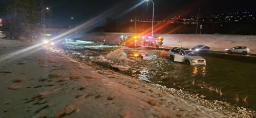 Firefighters stage at the side of a flooded highway in this handout photo, as the broken Bearspaw South Feeder Main, centre, spews water in Calgary, on Tuesday, Dec. 30, 2025. THE CANADIAN PRESS/Handout — Ian Royer (Mandatory Credit)