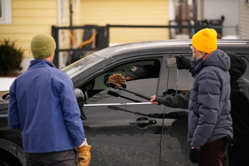 Bystanders film a federal immigration officer in their car Sunday, Jan. 11, 2026, in Minneapolis. (AP Photo/John Locher)