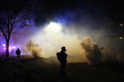 Law enforcement officers stand amid tear gas at the scene of a reported shooting Wednesday, Jan. 14, 2026, in Minneapolis. (AP Photo/Adam Gray)