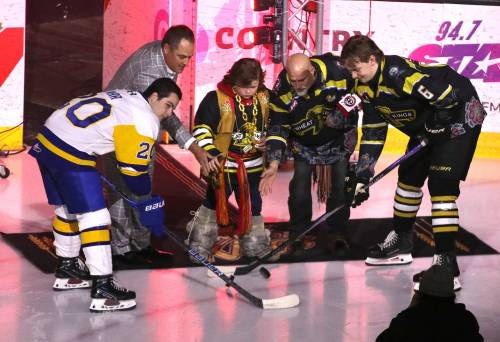 During the ceremonial opening faceoff, Brandon Wheat Kings owner Jared Jacobson, youngster Braxton Usunier and the Manitoba Métis Federation&rsquo;s Will Goodon drop pucks for Saskatoon Blades forward Tyler Parr and Wheat Kings defenceman Cameron Allard, who is Métis, prior to Western Hockey League action at Assiniboine Credit Union Place on Monday afternoon. (Perry Bergson/The Brandon Sun)