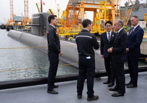 South Korea Prime Minister Kim Min-seok, centre, Prime Minister Mark Carney, second right, and National Defence Minister David McGuinty, right, are given a tour of the Hanwha Ocean Shipyard in Geoje Island, South Korea, Thursday, Oct. 30, 2025.  THE CANADIAN PRESS/Adrian Wyld