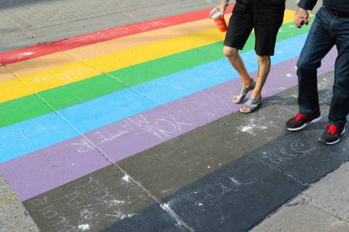 People walk on a Pride flag crosswalk in Calgary in August 2019. An Alberta town has passed a bylaw that effectively bans such crosswalks from public land. (The Canadian Press)