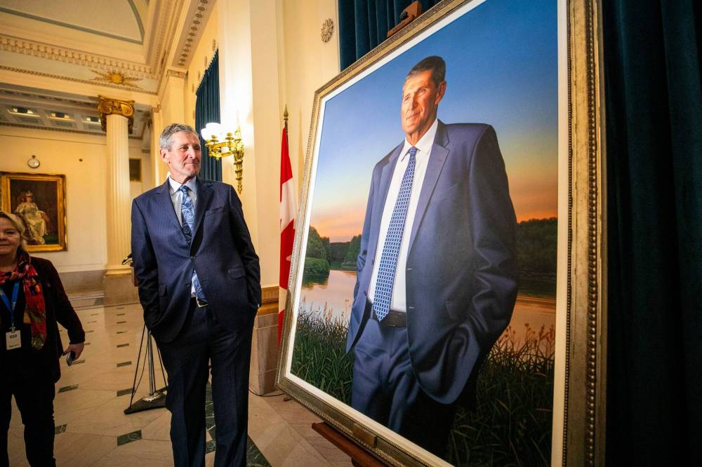 Former premier Brian Pallister at views his portrait at the Manitoba Legislative Building in Winnipeg after an unveiling ceremony on Thursday. The painting shows Pallister standing by the Assiniboine River near the community of High Bluff, with a sunset in the distance. (Mikaela MacKenzie/Winnipeg Free Press)