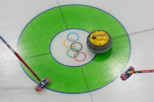 Britain team athletes sweep near the stone during the men's curling round robin session against United States at the 2026 Winter Olympics, in Cortina d'Ampezzo, Italy, Wednesday, Feb. 18, 2026. (AP Photo/Christophe Ena)