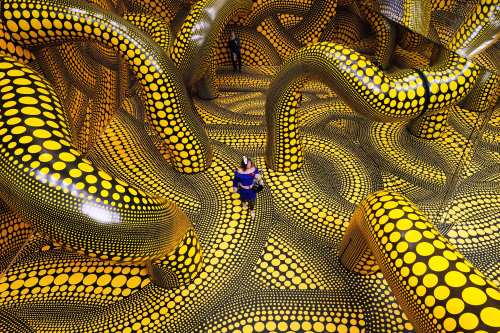 People walk through the artwork 'Infinity Mirrored Room' during a preview of the new major exhibition of legendary Japanese artist Yayoi Kusama at the Museum Ludwig in Cologne, Thursday, March 12, 2026. (AP Photo/Martin Meissner)
