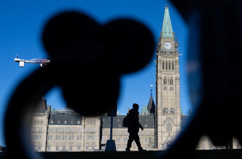 A man is silhouetted as buildings cast their shadows in front of the Peace tower on Parliament Hill, in Ottawa, Wednesday, Nov. 27, 2024. THE CANADIAN PRESS/Adrian Wyld