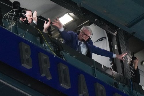 Broadcaster John Garrett acknowledges the crowd after his retirement was announced during a stoppage in play as the Vancouver Canucks and Calgary Flames play during the first period of an NHL hockey game in Vancouver, on Saturday, April 8, 2023. THE CANADIAN PRESS/Darryl Dyck