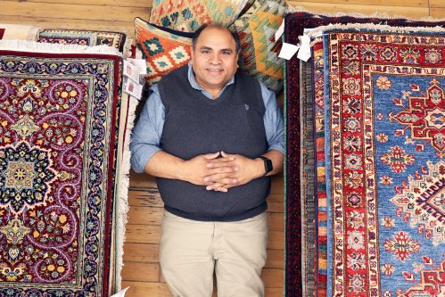 Yousaf Chaman, director for the Bunyaad fair-trade program, lies alongside some of the 268 hand-woven Pakistani rugs and pillows available for sale at the Ten Thousand Villages store on Rosser Avenue in Brandon on Thursday. See story on Page A2. (Tim Smith/The Brandon Sun)