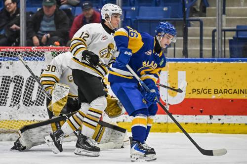 Brandon Wheat Kings defenceman Nigel Boehm (12) keeps an eye on Saskatoon Blades forward Cooper Williams (16) in front of goalie Filip Ruzicka during Western Hockey League action at SaskTel Centre on March 18. The defenceman is from nearby Corman Park. (Rick Elvin/Saskatoon Blades)
                                March 18, 2026