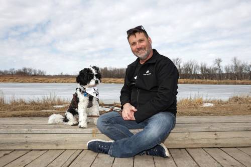 Canadian Armed Forces veteran Joel Langley, co-founder of Paws 4 Valour, sits with his dog, Bandit, at Dinsdale Park in Brandon on Friday afternoon. The program&rsquo;s upcoming session had an &ldquo;overwhelming response,&rdquo; Langley said. (Tim Smith/The Brandon Sun)
