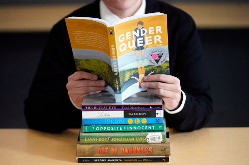 FILE - Amanda Darrow, director of youth, family and education programs at the Utah Pride Center in Salt Lake City, poses with books that have been the subject of complaints from parents, including 