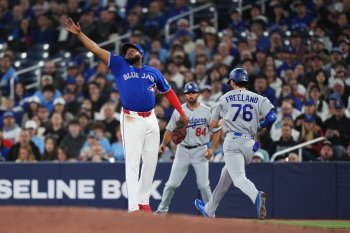 Toronto Blue Jays first baseman Vladimir Guerrero Jr. (left) can't get to ball thrown by pitcher Kevin Gausman (not shown) as Los Angeles Dodgers' Alex Freeland (76) reaches on a bunt during third inning MLB baseball action in Toronto on Tuesday, April 7, 2026. THE CANADIAN PRESS/Nathan Denette
