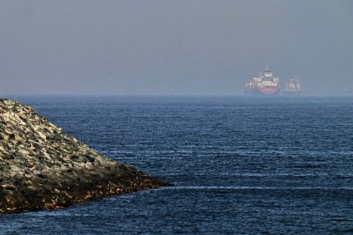 Cargo ships are seen at sea near the Strait of Hormuz, as viewed from a rocky shoreline near Khor Fakkan, United Arab Emirates, Friday, May 1, 2026. (AP Photo/Fatima Shbair)