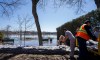 City workers construct a dike using sandbags near a flooded park as they prepare for flooding in Ile-Bizard, Que., on Friday, April 17, 2026. THE CANADIAN PRESS/Christinne Muschi