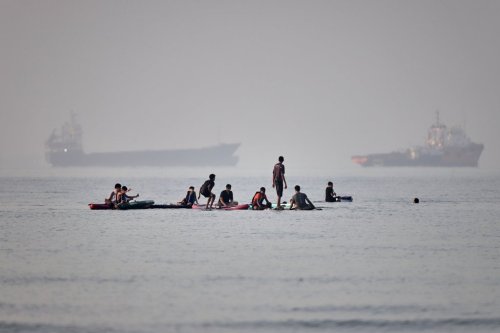 People gather on paddleboards in shallow water as cargo and service vessels are anchored in the Strait of Hormuz off Bandar Abbas, Iran, Monday, June 1, 2026. (Amirhosein Khorgooi/ISNA via AP)