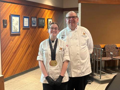 Coach Harold Fisher joins Crocus Plains Grade 11 student Kayla DeCosse, who won her second gold at Skills Manitoba, to present her creations to the Brandon School Division board of trustees and senior administration during the general board meeting last week. (Abiola Odutola/The Brandon Sun)