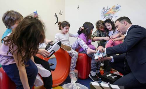 Finance Minister Adrien Sala helps a Grade 1 student, Emilie, put on her new shoes while handing out new shoes as part of a pre-budget event at Linwood Childcare Centre in March. (Ruth Bonneville/Winnipeg Free Press files)