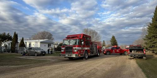 Fire trucks are parked by a trailer in Meadowbrook Village on Spruce Street on Saturday evening where a deck was on fire. (Photos by Alex Lambert/The Brandon Sun)