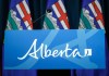Alberta flags are seen behind the podium in a media room in Calgary, on Friday, Oct. 17, 2025. THE CANADIAN PRESS/Jeff McIntosh