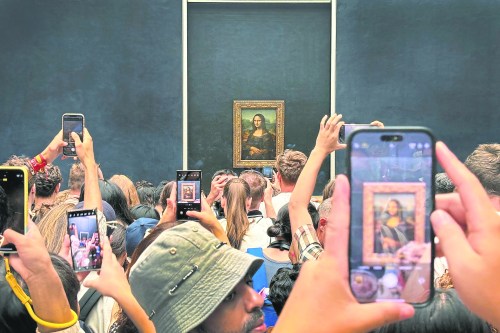 Tourists jostle each other to see and take a photograph of Leonardo da Vinci's painting of the Mona Lisa at the Louvre Museum in Paris, France, in August 2024. Nathan Murray takes a look at the value of human-made art in the age of artificial intelligence. (The Associated Press)