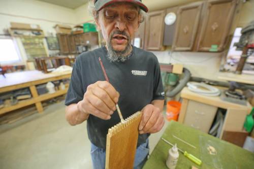Mike Stuart, a refinisher with nearly 30-years experience working at Persnickety, brushes glue onto the joints of a filing cabinet that a customer is having repaired. The cabinet is branded for an old company in Aberdeen, S.D. called News Printing Co., and features solid wooden dividers for organizing files. Stuart completely disassembled the piece, which was warped and non-functional, and repaired it by hand, filling in imperfections, sanding it into shape, and buffing down brass accents so that they shine again. (Connor McDowell/The Brandon Sun)