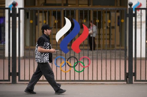 A man walks past a fence with Olympic Rings in front of the Russian National Olympic Committee building in Moscow, on Tuesday, July 7, 2026. (AP Photo/Pavel Bednyakov)