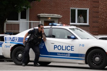 A person looks out of a window as police respond to a shooting in the Côte-des-Neiges district of Montreal on Monday. (The Canadian Press)