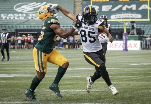 Hamilton Tiger-Cats' Kiondre Smith, right, holds off Edmonton Elks' Chelen Garnes during second half CFL football action in Edmonton, Saturday, Aug. 2, 2025. THE CANADIAN PRESS/Jeff McIntosh