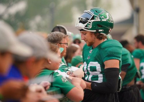 Saskatchewan Roughriders defensive back Jayden Dalke interacts with a fan after a spring training scrimmage was cut short due to wildfire smoke in Saskatoon, Sask., on Saturday, May 20, 2023. THE CANADIAN PRESS/Heywood Yu