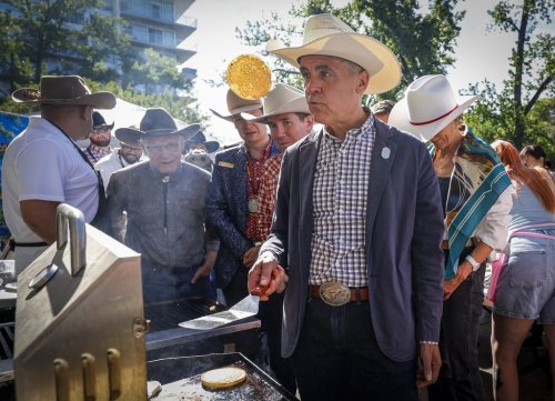Prime Minister Mark Carney, left, cooks pancakes at a Stampede breakfast in Calgary, Sunday, July 12, 2026. THE CANADIAN PRESS/Jeff McIntosh
