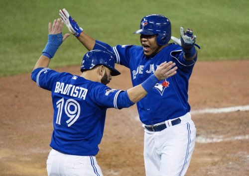 Blue Jays sluggers Jose Bautista, left, and Edwin Encarnacion celebrate scoring on a three-RBI double by Troy Tulowitzki during Game 5 of the American League Championship Series against the Kansas City Royals in Toronto on Oct. 21, 2015. THE CANADIAN PRESS/Darren Calabrese