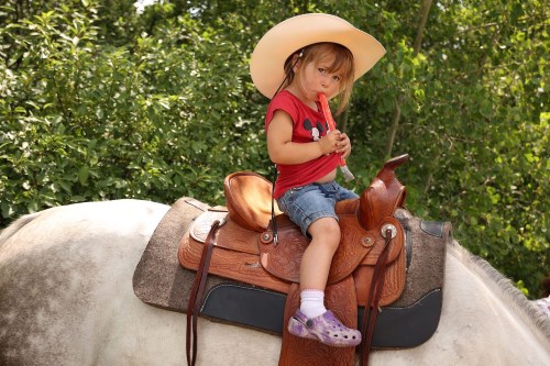 Two-year-old Thalia Passmore of Austin enjoys a freezie atop Julie, a quarter horse cross, at the Harding Fair on a hot and sunny afternoon. The fair is the one of the stops in a week of agricultural fairs in Westman known as The Milk Run. (Tim Smith/The Brandon Sun)