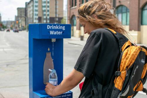 Jaunie Young, 28, refills a plastic bottle of water at a City of Winnipeg hydration station on Princess Street. Temperatures are expected to reach 37 degrees Celsius this weekend. (Brook Jones/Winnipeg Free Press)