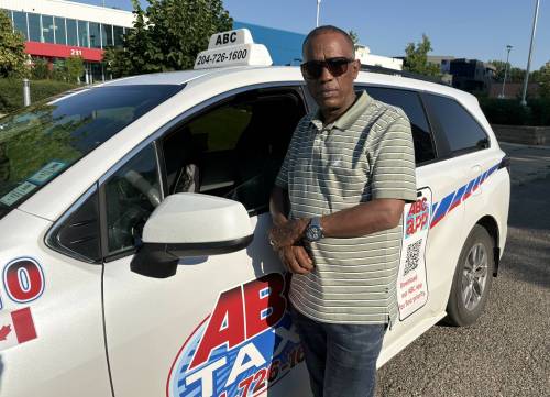 ABC Taxi president Abraham Takie stands in front of one of his cabs on Eighth Street in downtown Brandon on Friday. (Abiola Odutola/The Brandon Sun)