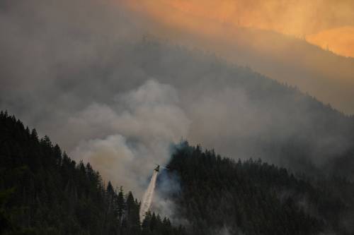 A helicopter drops water while fighting the Brunswick Creek wildfire in Boston Bar, B.C., on July 9. Scott Forbes asks someone to pass the sunscreen, as Prime Minister Mark Carney&rsquo;s government has abandoned measures intended to resist climate change. (The Canadian Press files)