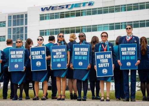 WestJet flight attendants hold a &ldquo;Day of Action&rdquo; while union members vote on a possible strike in Calgary on July 14. WestJet says it is continuing to bargain with the Canadian Union of Public Employees, which represents 4,400 flight attendants, in the hope of reaching agreement on a new contract. (The Canadian Press files)