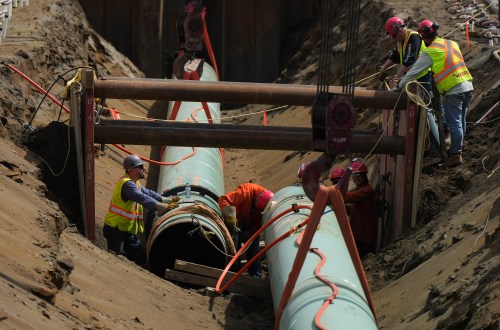 Workers place pipe during construction of the Trans Mountain pipeline expansion on farmland, in Abbotsford, B.C., on Wednesday, May 3, 2023. THE CANADIAN PRESS/Darryl Dyck