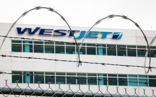 The WestJet headquarters building is seen through razor wire as WestJet flight attendants hold a 