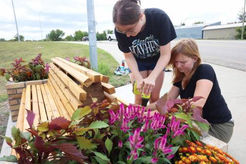 Architecture student Rebecca Grant and landscape architecture student Anastasia Zonenberg install a bench along Pacific Avenue in Brandon on Monday. (Tim Smith/The Brandon Sun)