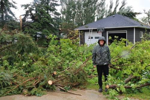 Michelle Martens stands outside her home in Elkhorn surrounded by broken trees after a tornado ripped through her backyard Sunday evening. (Rylee Gerrard/The Brandon Sun)
