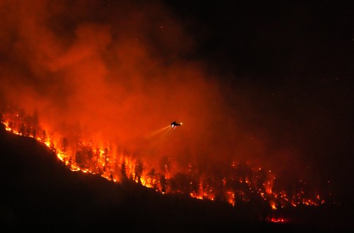 A helicopter conducting night operations prepares to drop water on the Quilpituk Creek wildfire burning on the west side of Okanagan Lake near Fintry, B.C., late Monday, Aug. 3, 2026. THE CANADIAN PRESS/Darryl Dyck