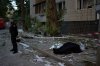 A policeman stands next to the bodies of two people killed during an overnight Russian attack in Kyiv, Ukraine, Thursday, Aug. 20, 2026. (AP Photo/Francisco Seco)
