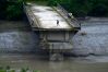 People stand on remnants of a bridge which spanned across Trishuli river and was washed away in flash floods, in Dhading District, Nepal, Sunday, Aug. 30, 2026. (AP Photo/Niranjan Shrestha)
