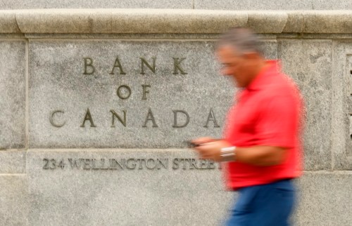 A man checks his phone as he walks past the Bank of Canada building in Ottawa, Wednesday, July 15, 2026. THE CANADIAN PRESS/Adrian Wyld